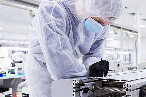 Person wearing protective equipment in a laboratory or high-tech factory.